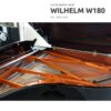 Un piano à queue neuf Wilhelm W180 avec son intérieur orange et des cordes visibles, numéroté NS: 019.759.