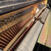 Mécanisme intérieur d'un piano droit, montrant les marteaux, cordes et étouffoirs, illustrant la complexité de l'instrument.
